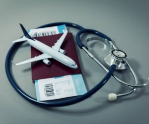 travel insurance - passport with flight ticket and stethoscope on gray background