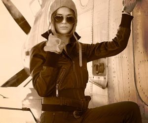 Beautiful girl in jacket standing next to war aircraft. Retro  photo.